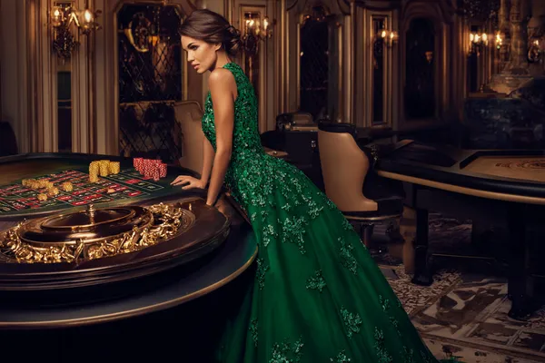 DB9 — A high-class gaming experience without limits A woman in a luxurious green gown next to an ornate roulette wheel, capturing the upscale casino mood of DB9.